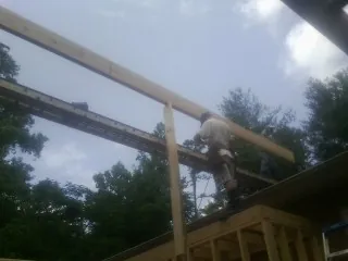 Carpenter setting a ridge beam over a new addition frame — Ice Dam Removal by Roofing Brothers in Ridgecrest