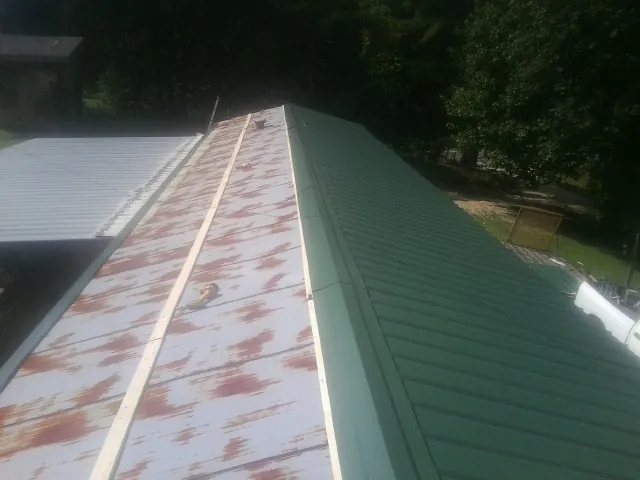 Old rusted panels beside newly installed green metal roofing — Wind Damage Roof Repair by Roofing Brothers in Ridgecrest
