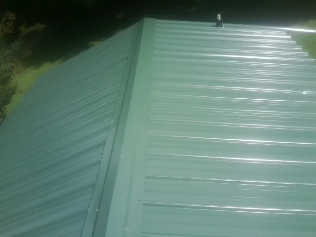 New green metal panels meeting at the ridge of a roof — Flat Roof Repair work by our crew in Ridgecrest