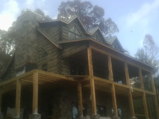 Stone chimney and dormers on a large log home with a timber porch in Ridgecrest