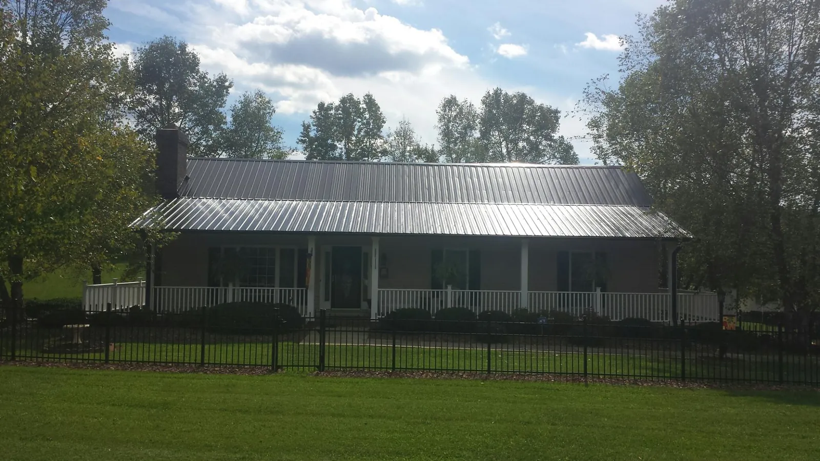 Gray metal roof on a brick ranch with a full width front porch — Gutter Guard Installation work by our crew in Ridgecrest