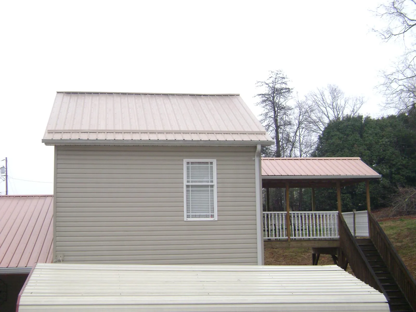 Tan metal roofs on a two story addition and attached porch, from a Roof Replacement job in Ridgecrest