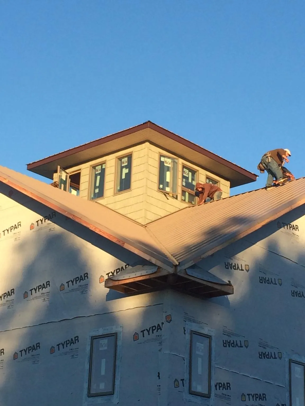 Roofers working around a rooftop cupola on a new metal roof at sunset — Roof Waterproofing in Ridgecrest by Roofing Brothers